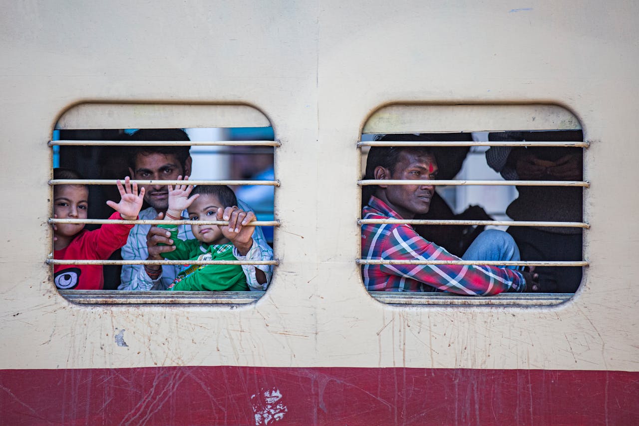 A heartwarming view of passengers including children looking out from a train in Jaipur, India, creating a sense of curiosity and travel.