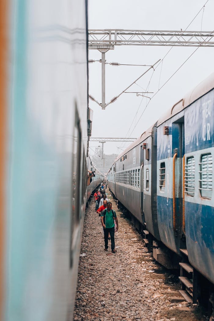 Passengers walking between two trains at a bustling railway station, capturing the essence of travel.